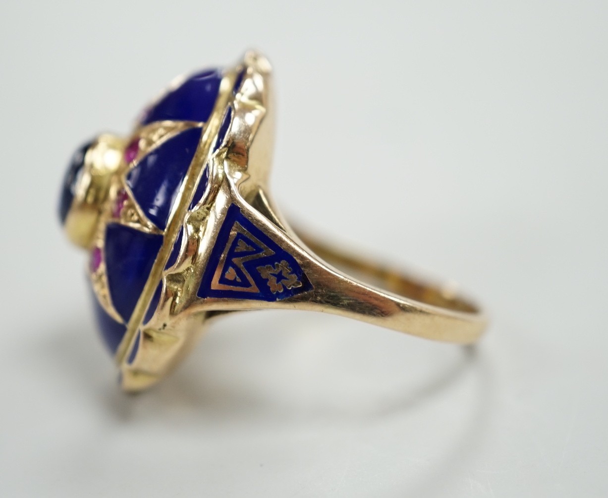 A yellow metal, blue enamel, ruby and cabochon sapphire set oval dress ring, the shank inscribed 'Sister My Sister?' size O, gross weight 13.7 grams.